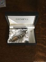 Watch in original Geneva-branded black case with satin lining and price tag showing $25.00