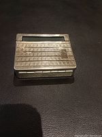 Front view showing textured grid pattern and engraving plaque on the metal rolling machine case