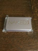 Sealed metal tin packaging of Urban Decay Naked 3 brush set, front view with branding visible.