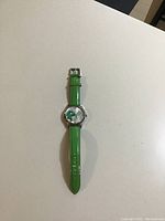 Full watch view showing green leather band with visible wear and stainless steel case.