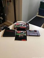 Photo of the Super Nintendo Relief Pitcher game cartridge, black plastic case, instruction booklet, and game box arranged on a white surface.