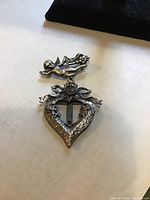 Front view of Victorian brooch showing angel figure and heart frame with floral details and hollow center