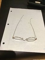 Top down view of glasses on lined paper showing thin wireframe and oval lenses