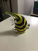 Side angle showing yellow and black striped glass fish with clear fins on a white surface.