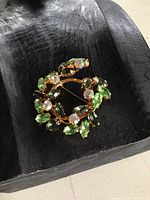 Photo of the vintage rhinestone brooch resting in a black textured dish showing the detail of rhinestones and gold-setting.