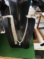 Front view of vintage rhinestone choker with three front split segments displayed on black bust stand.