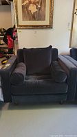 Front view of the velvet arm chair with pillows, showing the shape, fabric, and cushion details clearly.