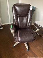 Full view of brown leather office chair on wheels with beige armrests and beige base.