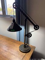 Full view of the Pottery Barn adjustable table lamp showing the pulley system and conical shade.