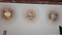 Three 31 inch metal framed starburst mirrors hung on wall in a row