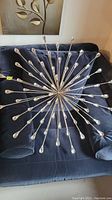 Full view of the starburst wall art with metal rods and faux crystal ends, placed on a dark blue velvet couch.