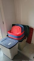 Overall view of stacked storage totes with lids of various colors including red, navy blue, and dark green.