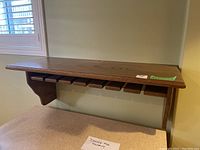 Full view of the wood wall-mounted bar shelf showing the integrated stemware rack beneath the shelf.