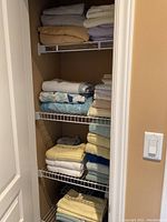 Closet with folded bed linens, towels, and bath mats showing color variety and arrangement on wire shelves