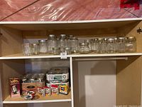 Shelf with assorted glass canning jars and metal lids, plus unopened boxes