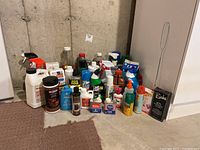 Image showing a variety of cleaning and polishing products on the floor including spray bottles, liquid containers, and insect repellent cans.