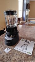 Full view of assembled Cuisinart blender with glass jar and instruction manual on counter.