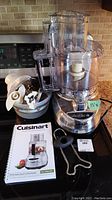 Full view of Cuisinart food processor with accessories and instruction manual on countertop in kitchen environment.