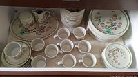 Drawer with stacked dinner plates, side plates, mugs, saucers and platter with creamer set
