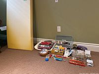 Wide shot showing full lot with large yellow foam piece against wall and various sewing supplies spread on floor including fabric, threads, scissors, buttons, and tools.