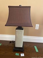 Front view of the table lamp showing the ceramic crackled glaze base with dark wooden accents and the square brown fabric lampshade.