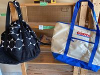 Photo of Thirty-One black and white polka dot tote bag and Costco beige and blue insulated cooler tote bag hanging on a wooden pegboard stand.