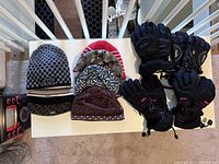 Lot overview showing five adult winter hats and four pairs of black winter gloves laid out on a white table.