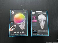 Front and back of two Smart Tech wireless LED smart bulb boxes side by side showing product details and packaging in new condition.