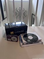Nikon Coolpix S210 camera box, Nikon Coolpix exterior image, software CD and manuals laid out beside box.