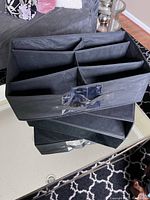 Three black folding cloth shoe organizers stacked, showing 6 divided compartments for shoes or small items storage.