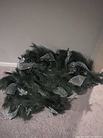Photo showing a coiled bundle of artificial green holiday garland decorated with silver ribbon placed on carpet.