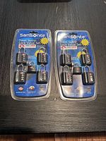 Two unopened blister packs each containing four Samsonite Travel Sentry combination luggage locks, blue packaging with instructions and logos.
