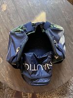 Top-down view of the Nautica bag showing the interior and main compartment zipper open with the Nautica logo pocket visible.