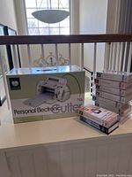 Cricut Personal Electronic Cutter machine box with stacked Cricut cartridges in packaging