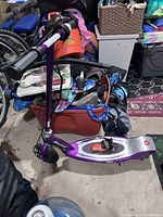 Full side view of the purple Razor electric scooter showing footboard, handlebars and wheels.