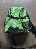 Front view of bright green Speedo backpack showing multiple zippered compartments and Speedo logo on front pocket.