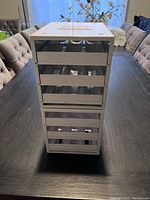 Two white stackable and retractable spice racks stacked vertically on a table