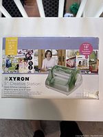 Box showing the product image, brand, and specifications for the 5" Xyron Creative Station sticker machine.