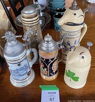 Overview of the five beer steins with various designs and metal lids