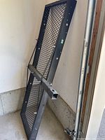 Steel mesh cargo carrier standing upright against wall, showing mesh platform and metal frame construction with hitch mount tube.