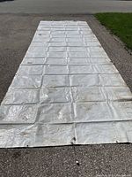 Long rectangular white tarp laid flat on ground, showing size and condition with some dirt marks.