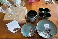 Set of four Cuisinart Blue Peony dishes including dinner plates, bowls, dessert plates with four Nordic tea mugs, and martini glasses viewed from above on a wooden table.