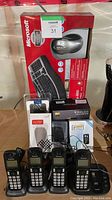 Full lot contents showing boxed Microsoft Wireless Laser Desktop 4000 keyboard and mouse, Panasonic cordless phones, Plantronics earpiece, and other electronics.