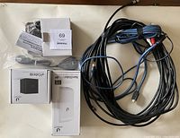 All items laid out on beige carpet: Ubiquiti NanoStation locoM2 box, Ubiquiti airCube ISP box, video/audio RF modulator, several cables including HDMI and RCA.