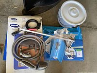 Overview of health aid items including walker tray boxes, personal grabber, shower extension hose with showerhead, car door handle support and blue commode pail