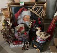 Lot of indoor Christmas decorations including framed Santa print, wire Christmas tree, candle holding reindeer, metal sign, mat, tin, box, and assorted small decorations.