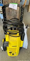 Front view of yellow Karcher power washer model K 2.56 with coiled hose and attached spray gun.
