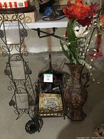 Metal wall hanging with three glass candle holders and wire scroll design; magazine holder with decorative plaque; tall patterned metal vase with artificial flowers; small decorative basket