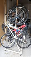 Side view of bicycle tree stand holding 3 bikes and 3 spare wheels, showing stand structure and bike details.