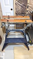 Front view of portable foldable metal workbench showing wooden jaws and cast metal frame